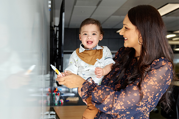 Photo of mother working at whiteboard holding child